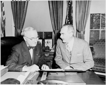 Photograph of President Truman at his desk in the Oval Office with Secretary of State Dean Acheson, discussing... - NARA - 200263