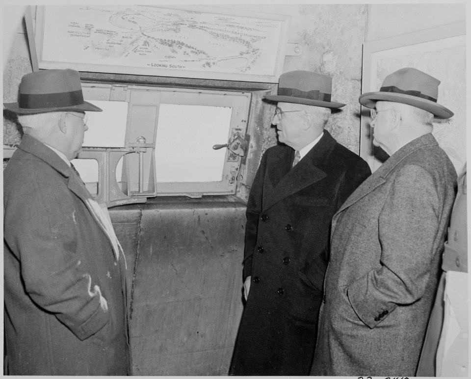 Photograph of President Truman and Secretary of the Interior Harold Ickes, with others, looking out a window from... - NARA - 199295