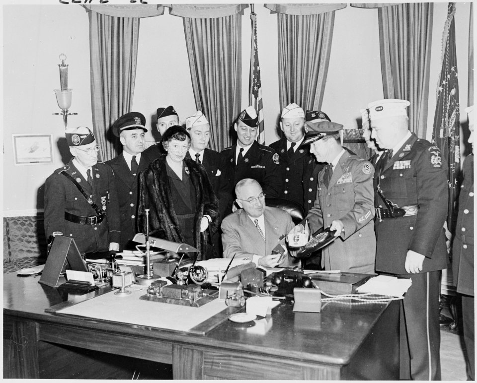 Photograph of President Truman at his desk in the Oval Office, receiving a gold life membership card and plaque from... - NARA - 200258