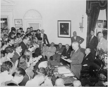 Photograph of President Truman in the Oval Office, reading the announcement of Japan's surrender to assembled... - NARA - 199168 photo