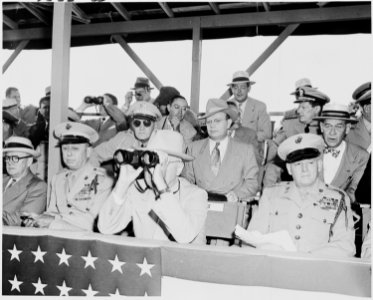 Photograph of President Truman peering through binoculars, with other dignitaries, watching war games involving... - NARA - 200216