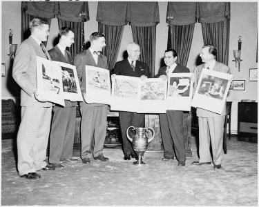 Photograph of President Truman in the Oval Office, posing with photographers and their winning photographs in the... - NARA - 200112 photo