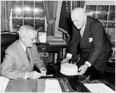Photograph of President Truman receiving a birthday cake at his desk in the Oval Office from White House receptionist... - NARA - 200315