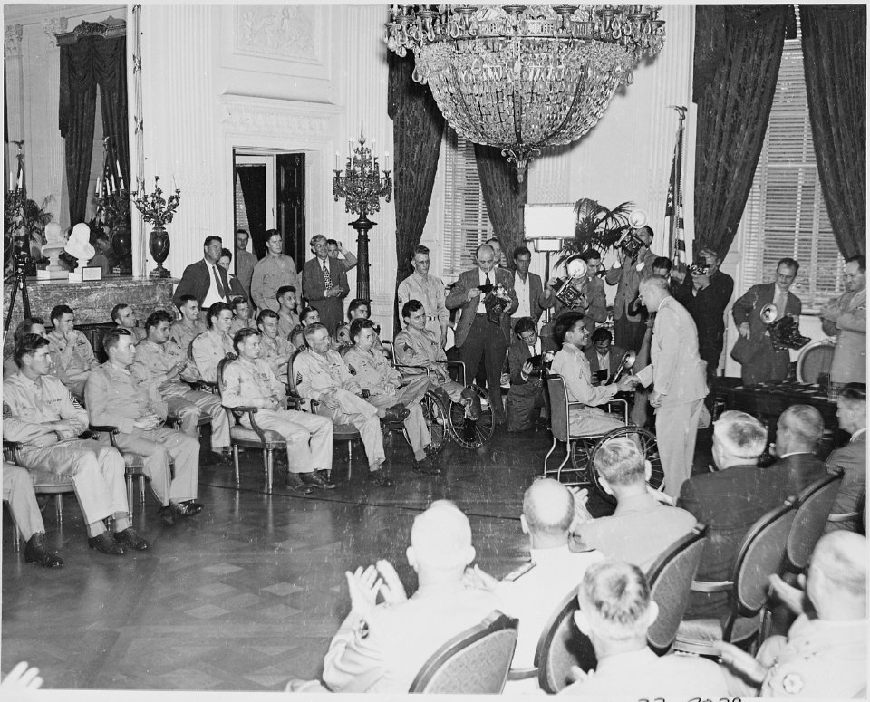Photograph of President Truman shaking hands with a Medal of Honor recipient in a wheelchair, while other recipients... - NARA - 199192