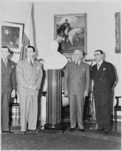 Photograph of President Truman receiving a marble bust of Simon Bolivar from a Venezuelan delegation in the Oval Office. - NARA - 199532