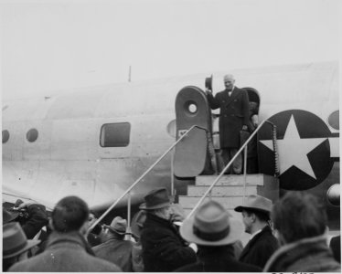 Photograph of President Truman waving his hat to the crowd from the door of his airplane at Washington's National... - NARA - 199288 photo