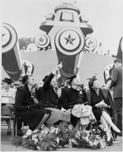 Photograph of the family of Admiral Chester Nimitz, seated on speaker's platform in front of mock-up of battleship. - NARA - 199210