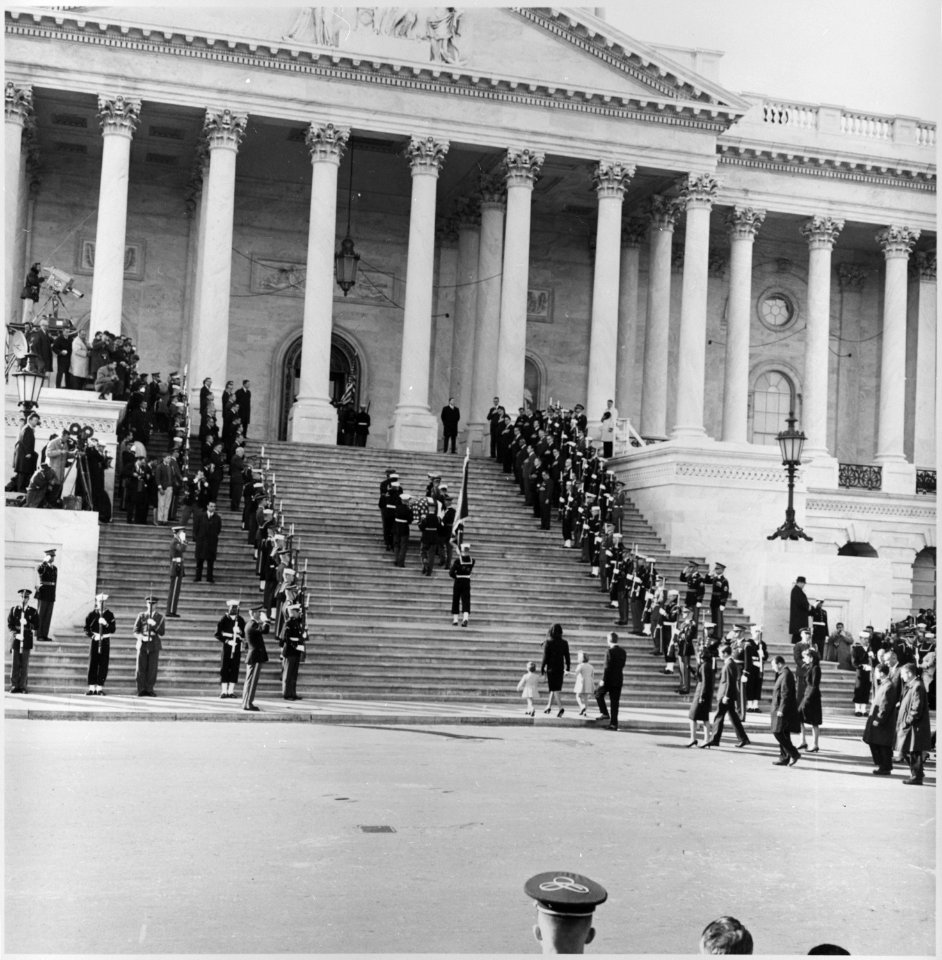 Photograph of servicemen carrying the casket of President John F. Kennedy up the steps of the Capitol, followed by... - NARA - 200443