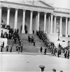 Photograph of servicemen carrying the casket of President John F. Kennedy up the steps of the Capitol, followed by... - NARA - 200443