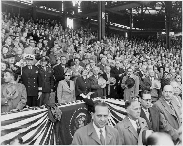 Photograph of the President and Mrs. Truman, with other dignitaries, saluting the flag at Griffith Stadium in... - NARA - 200291