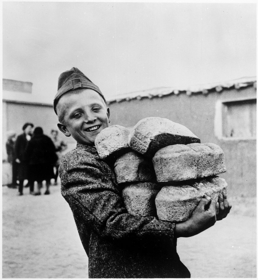 Polish youngster with his arms loaded down with bread made from flour supplied by the American Red Cross. Smile is in... - NARA - 531156