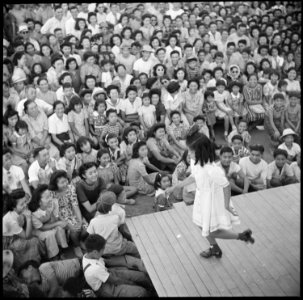 Poston, Arizona. A young evacuee of Japanese ancestry entertains her fellow evacuees with a demonst . . . - NARA - 538562 photo