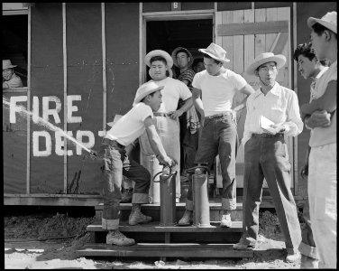 Poston, Arizona. Evacuee Firechief, Tom Nishimura, discusses Army type fire extinguisher with his s . . . - NARA - 536093