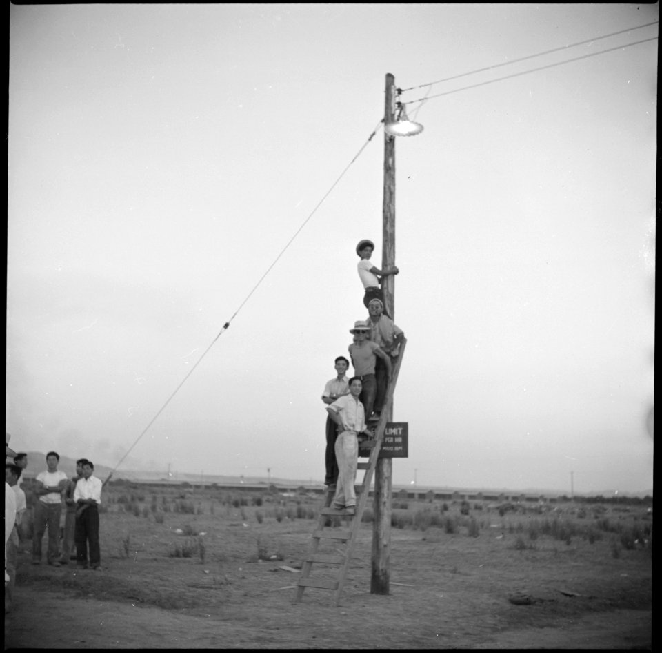 Poston, Arizona. Evacuees of Japanese ancestry watching from their positions on a light pole an out . . . - NARA - 538554