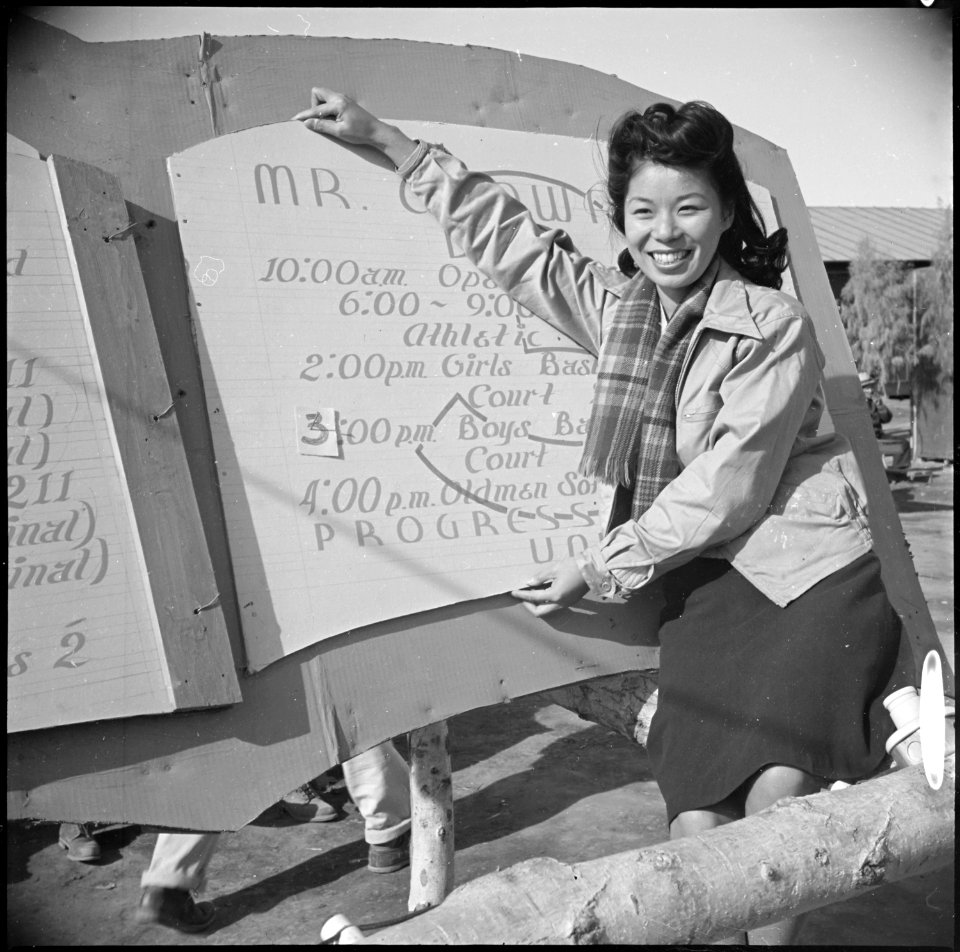 Poston, Arizona. New Years Fair. Pretty Nami Nadaoka is shown with the program sign at the fair, w . . . - NARA - 536641