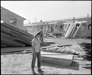 Poston, Arizona. Site Number 1. Larry Orida watches erection of the hospital at this War Relocatio . . . - NARA - 536075 photo