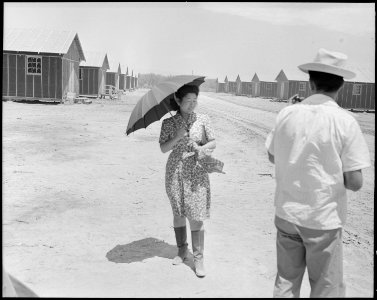 Poston, Arizona. This evacuee is fortified with an umbrella for protection from the sun, and high- . . . - NARA - 536145