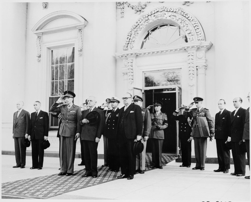 President Truman and Prince Charles of Belgium at attention, with other dignitaries, in the entrance to the White House. - NARA - 199765