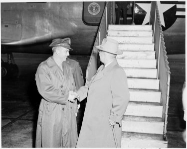 President Truman at the bottom of the stairs leading up to the presidential airplane, shaking hands with pilot Henry... - NARA - 199673 photo