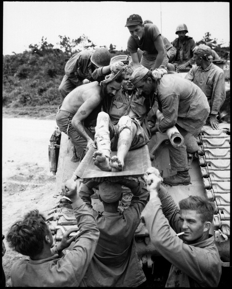 Private W. D. Fuhlrodt is removed from the tank which carried him from the front lines. Japanese artillery and small... - NARA - 532562