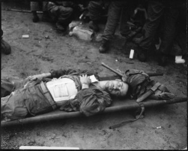 Private First Class, Thomas Conlon, 21st Infantry Regiment, lies on a stretcher at a medical aid station, after being... - NARA - 531376 photo