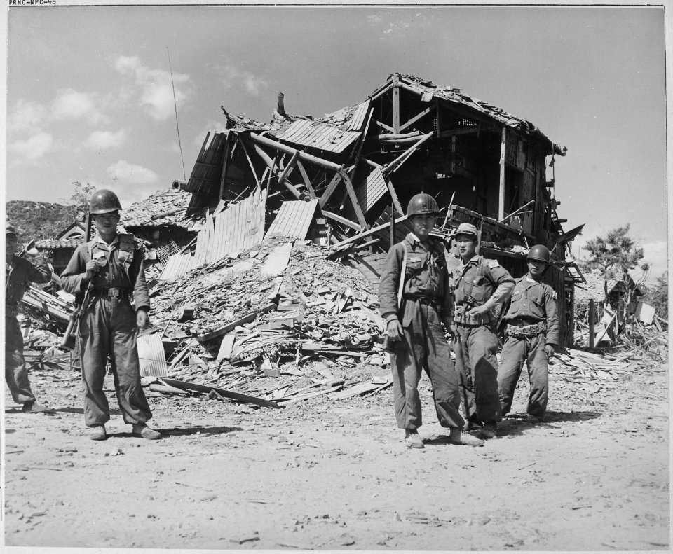 Republic of Korea military police pose before the ruins of a devastated building in Pohang. Most buildings that... - NARA - 520773
