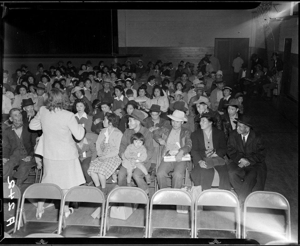 Salinas, California. Seated in family groups, evacuees of Japanese ancestry check in at Armory befo . . . - NARA - 536188