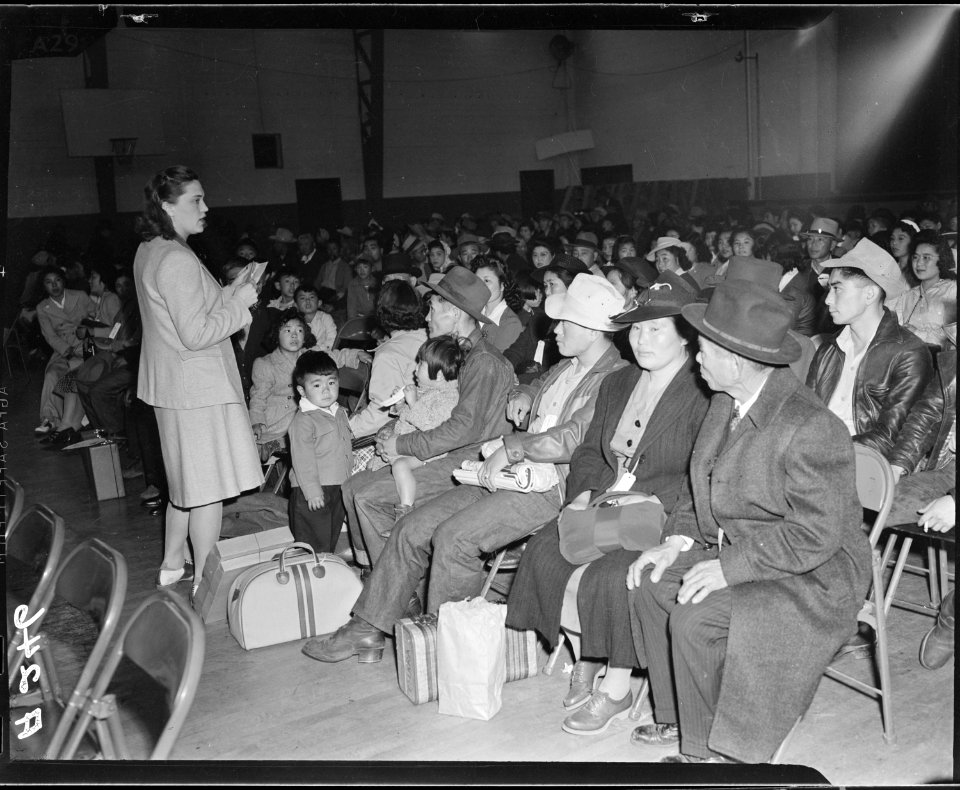Salinas, California. Seated in family groups, evacuees of Japanese ancestry check in at Armory befo . . . - NARA - 536190