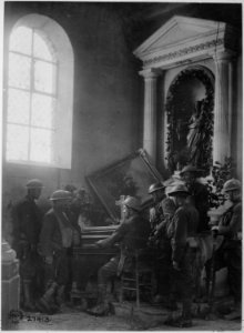 Squad of American soldiers listening to one of their comrades playing the organ in the half-wrecked old church in... - NARA - 530768