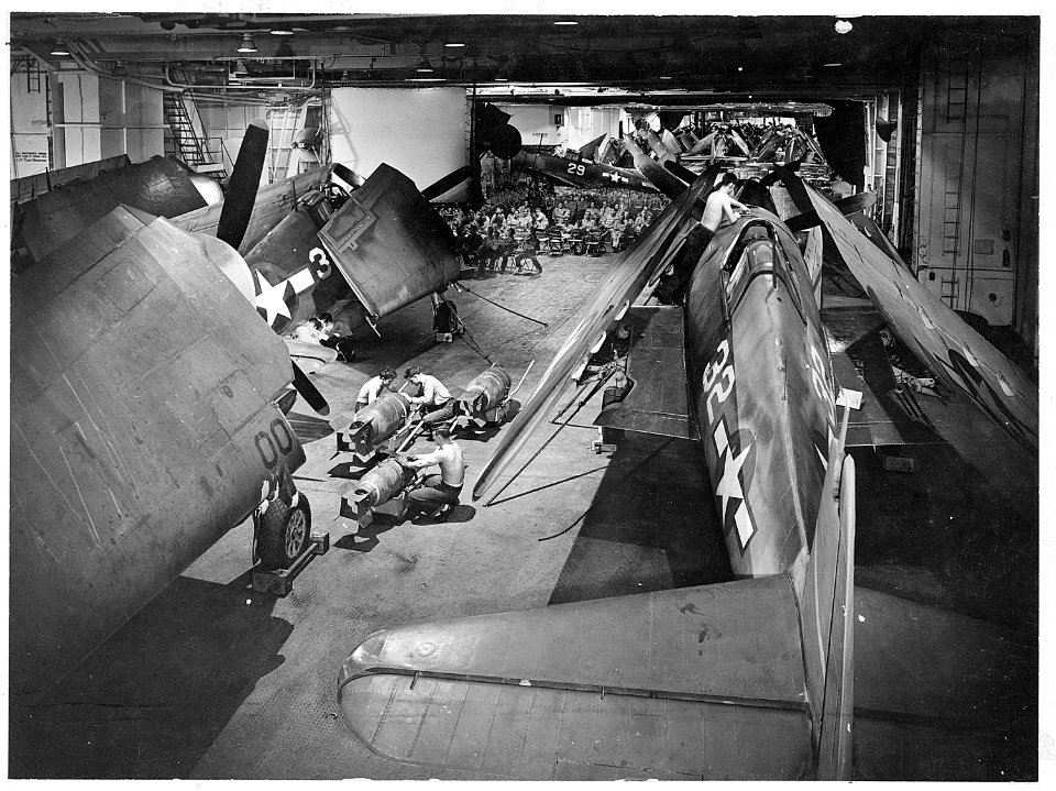 Surrounded by F6F's ordnance men work on bombs on hangar deck of USS Yorktown (CV-10). Officers and men in background... - NARA - 520771