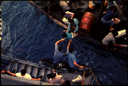 South China Sea....Crewmen of the amphibious cargo ship USS Durham (LKA-114) take Vietnamese refugees aboard a small... - NARA - 558518