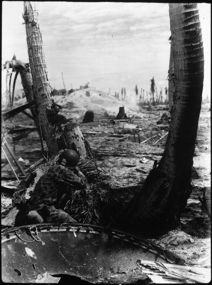 Taking the slim protection that a blasted tree affords, this Marine picks-off the Japanese in a pill box. A Japanese... - NARA - 532518