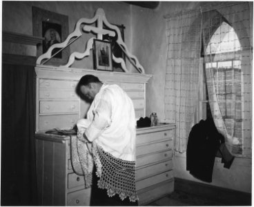 Taos County, New Mexico. Father Morgan puts on vestments for Mass in vestry of church at Arroyo Hon . . . - NARA - 521915
