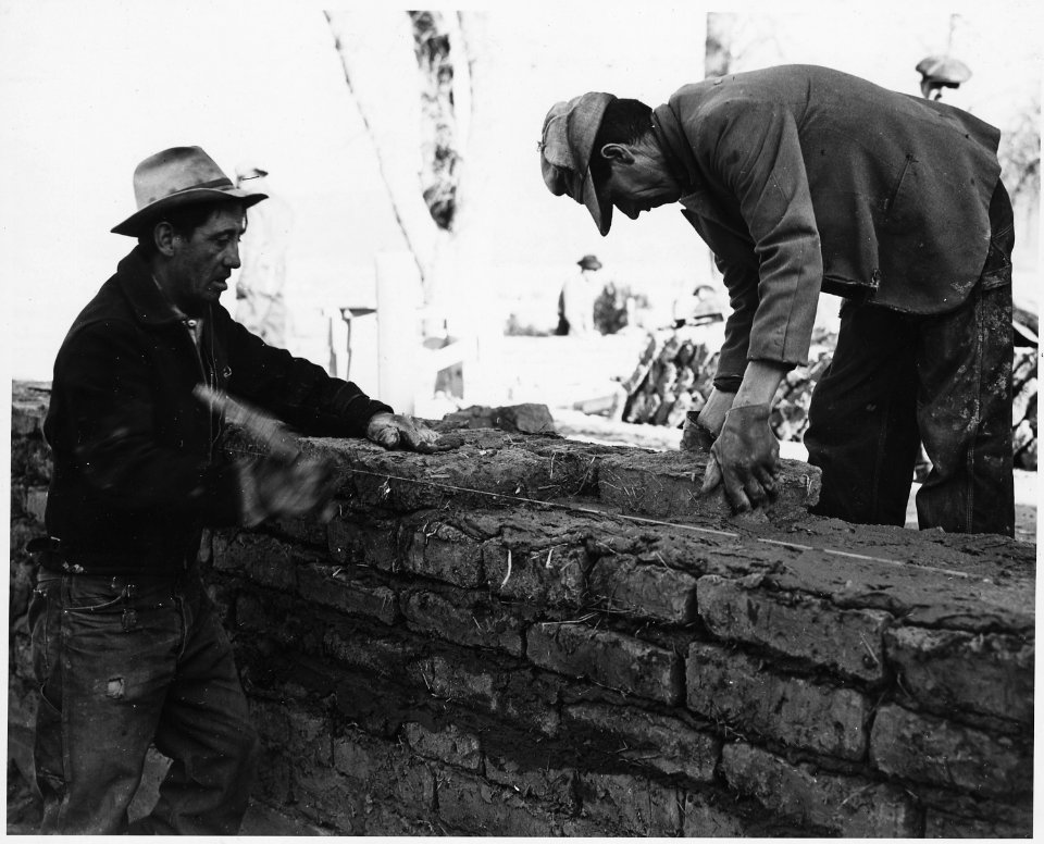Taos County, New Mexico. Laying adobe bricks with adobe and plaster, building addition to the Holy . . . - NARA - 521982
