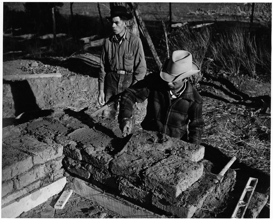 Taos County, New Mexico. Laying adobe bricks with adobe and plaster, building addition to the Holy . . . - NARA - 521981