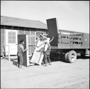 Topaz, Utah. Tables made on the project by volunteer workers being delivered to barracks rooms, whi . . . - NARA - 538692