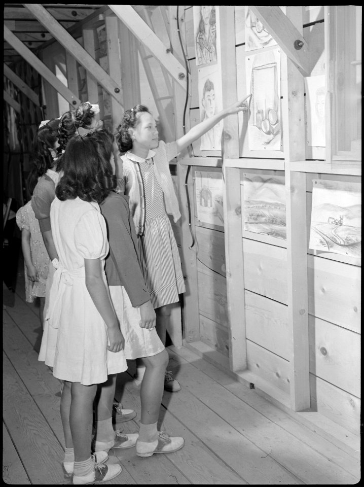 Tule Lake Relocation Center, Newell, California. An evacuee girl proudly shows friends her art work . . . - NARA - 538406