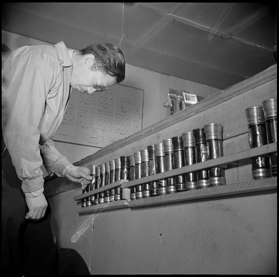 Tule Lake Relocation Center, Newell, California. An evacuee warden inspects flashlight equipment, w . . . - NARA - 536921