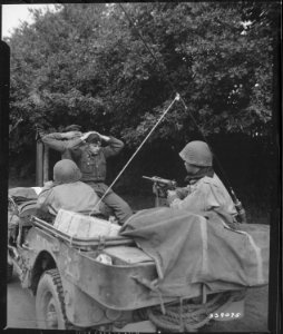 Two German prisoners of war are being taken to the 6th Division Prisoner of War Encampment for interrogation and... - NARA - 531358