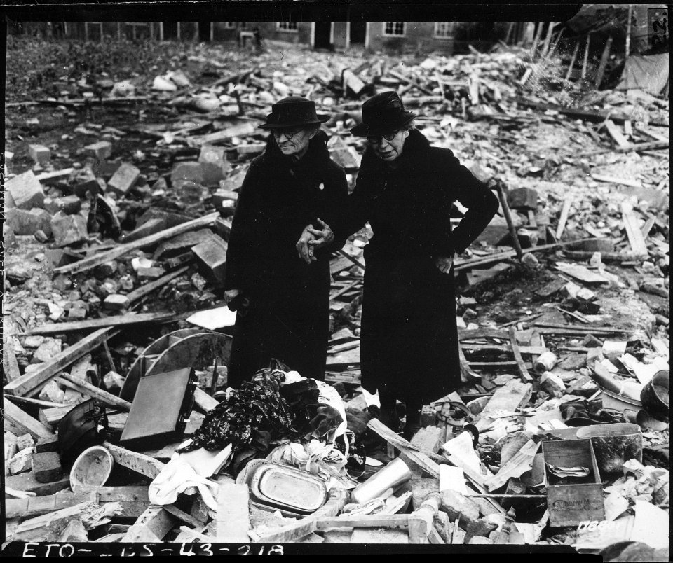 Two bewildered old ladies stand amid the leveled ruins of the almshouse which was Home, until Jerry dropped his... - NARA - 531162