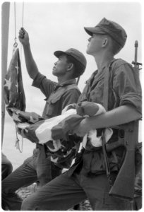 Vietnam....Marine Lance Corporal Coy L. Hester Jr., right, 19, raises the American flag with the help of a Vietnamese... - NARA - 532495 photo