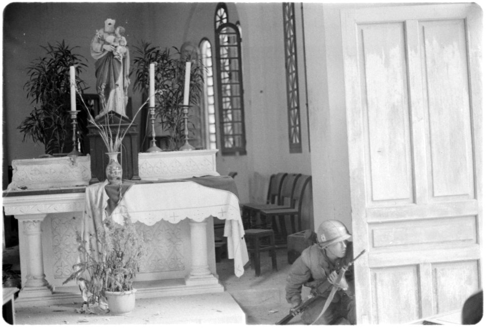 Vietnam....A member of Company A, 1st Battalion, 1st Marines, crouches behind a church door as he checks for the... - NARA - 532453
