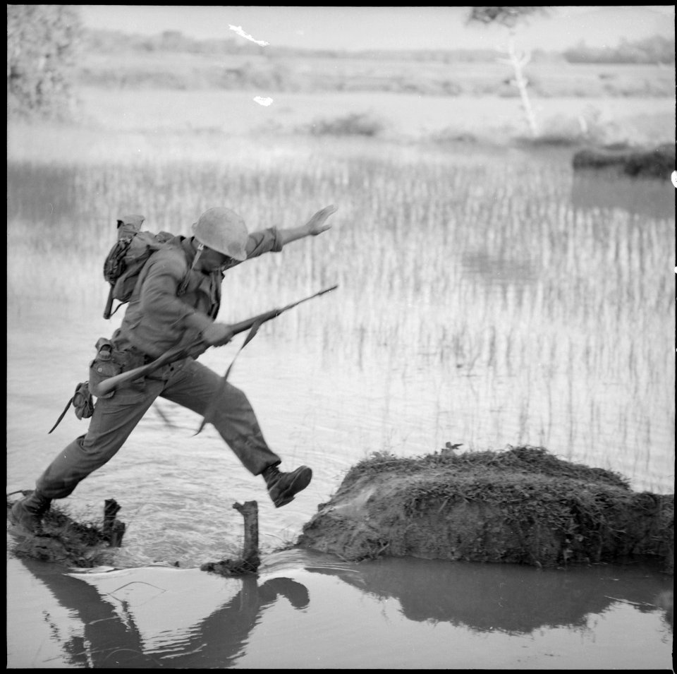 Vietnam....A Marine rifleman with Company H, 2nd Battalion, 5th Marines, Leaps across a break in a rice paddy dike... - NARA - 532474