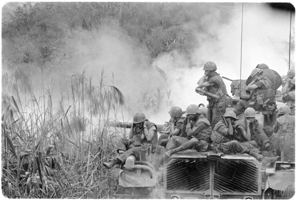 Vietnam....Marines riding atop an M-48 tank cover their ears as te 90mm gun fires during a road sweep southwest of... - NARA - 532483