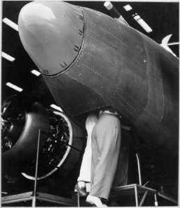 Workmen at the Vega aircraft plant, Burbank, California Two women employees working through the bombardier's hatch. - NARA - 520739