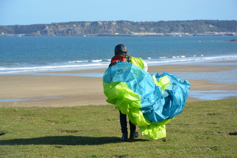 Wing folded veil folded color blue green paraglider in front of the sea