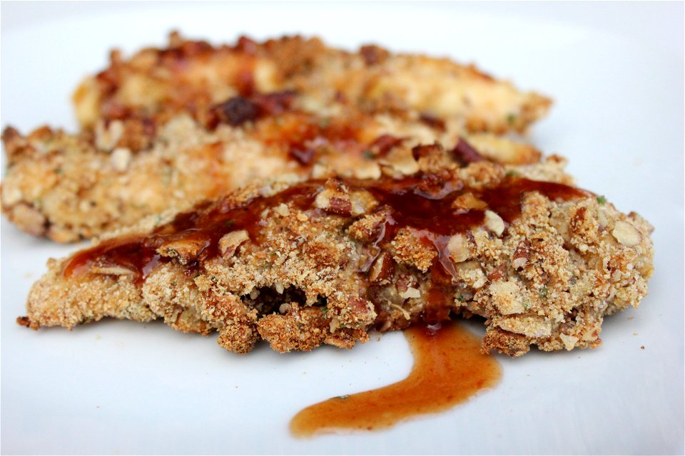 Chicken tenders covered in breadcrumbs, flour, nutmeg, orange zest and pecans. Sauce topping created with maple syrup, honey barbecue sauce, navel orange, and extra virgin olive oil.