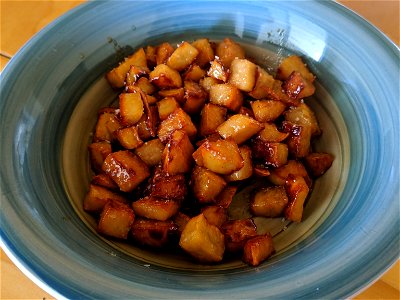 This is an image of a bowl of chopped sweet potato that has been sauteed with honey. photo