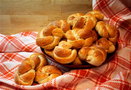 A wooden bowl of newly-baked cardamom buns on a checkered linen tablecloth in Lysekil, Sweden. Focus stacking of 6 pictures (using Photoshop).. (30-40 buns): Ingredients: 5 dl milk, 50 g yea photo