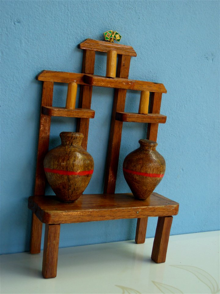 Arte de madeira e fruto da palmeira babaçu formando uma miniatura de banco de pote.